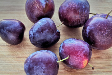 Ripe plums on a wooden rustic table.