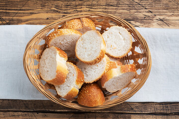 Fresh white bread, baguette slices in a wicker basket. Wooden rustic table background. Close up