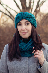 A beautiful young girl in a warm knitted snood and a headband. DIY knitting
