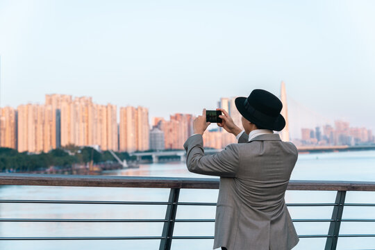 Asian businessman is using mobile phone to take pictures of the city view.
