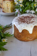 Easter cake with glace icing and spring flowers. Postcard with Easter bread. Christian traditions. White wooden background.