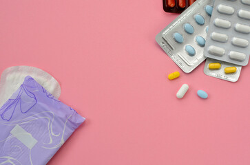 pads and pills on a pink background, flat lay