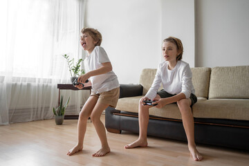 Funny caucasian siblings passionately playing video games in front of tv, two brother sister...