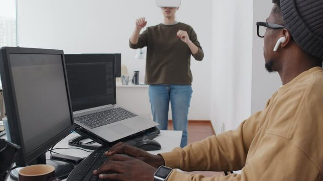 Selective focus shot of ethnically diverse game developers working together in office using VR or AR technology