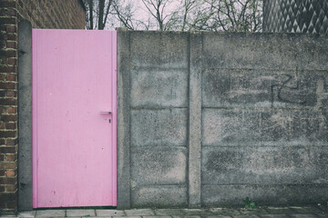 pink door in a concrete fence