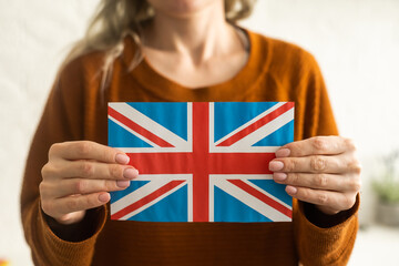 Hand holding flag of UK, isolated on white background