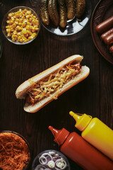 Hot dog on a wooden board. American fast food with sausage, cheese and mustard on a wooden table. Photo from the top.