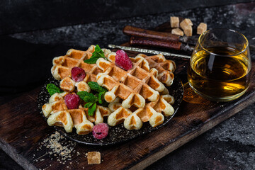 Belgian waffles with raspberries and mint on a dark plate
