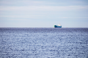 Distant view with a ship in the sea with a blue sky