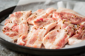 Whole pepper and raw pork belly in an oven pan
