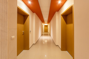 Perspective corridor of condominium. Modern and bright interior in the hotel. Long hallway with doors