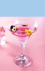Glass of pink violet purple cocktail decorated flowers viola pancies