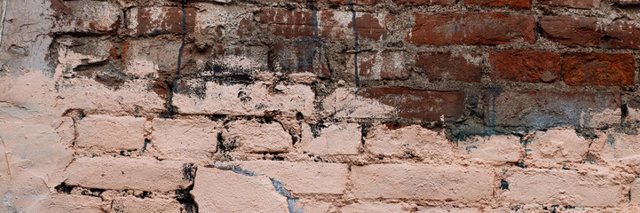 Old brick wall with peeling stucco. Weathered rough wall surface with brickwork. The wall is...