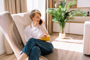 Cheerful woman speaking on smartphone at home