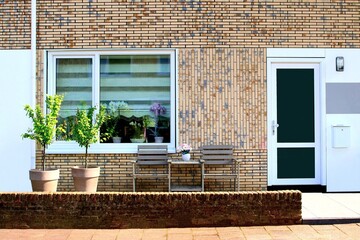 Front of Dutch brick wall house with door, plants and lounge chairs, Netherlands