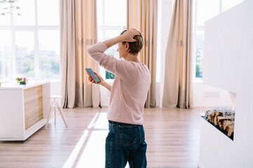 Adult woman looking at smartphone while standing in spacious room