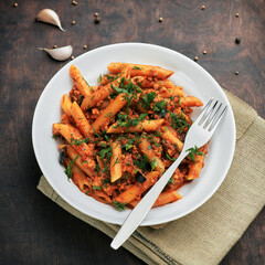 Traditional Italian cuisine: tasty pasta with bolognese sauce. Yummy macaroni (penne rigate) on rough wooden table. Square