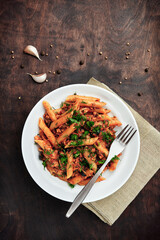 Traditional Italian cuisine: tasty pasta with bolognese sauce. Delicious macaroni (penne rigate) on rough wooden table. Top view. Copy space