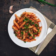 Traditional Italian cuisine: tasty pasta with bolognese sauce. Delicious macaroni (penne rigate) on rough wooden table. Top view. Square