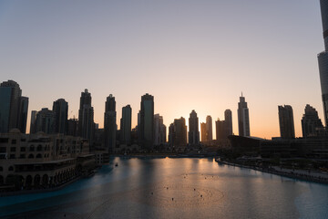 Dubai singing fountains at night lake view between skyscrapers. City skyline in dusk modern architecture in UAE capital downtown.