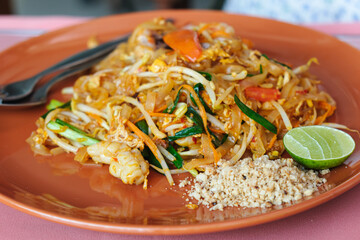Pad thai is a classic Thai dish of fried rice noodle with vegetables and aromatic sauce. Dish of rice noodles with seafood - shrimp, squid. Thai Fried Noodles Pad Thai with shrimp and vegetables