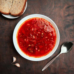 Borsch in plate on rough wooden table, a traditional Russian and Ukrainian soup. Borscht, a dish of Slavic cuisine. Top view. Square