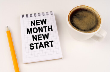 On a white surface, a cup of coffee, a pencil and a notepad with the inscription - NEW MONTH NEW START