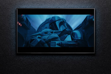 Obraz premium TV screen playing Mandalorian trailer or movie. TV on black textured wall. Moscow, Russia - January 18, 2023.