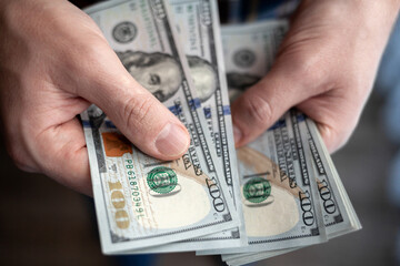 Close up male hand Counting and holding money us dollar. The concept of financial business and crisis.