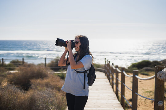 Female photographer taking photos on camera near ocean