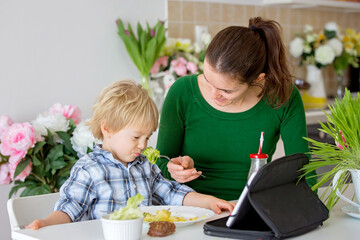 Little toddler child, blond boy, eating boiled vegetables, broccoli, potatoes and carrots with fried chicken meat at home