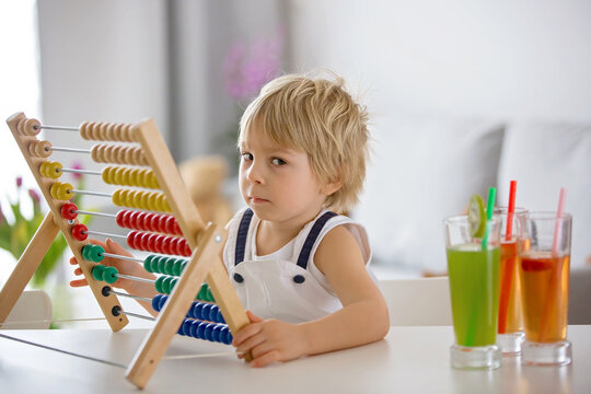 Sweet toddler child, blond boy, learning math at home with colorful abacus