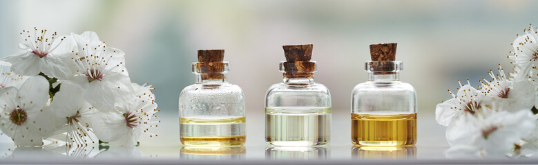 Banner with essential oil bottles with white cherry blossoms