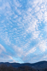 Obraz premium Distant hills under blue sky with cirrocumulus clouds, evening light