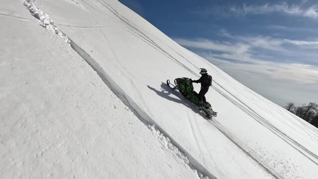 Aerial fpv view professional mountain biker snowmobile performing trick stuntrading driving rear truck wheelie and 180-degree turn. Stunt riding winter wilderness frozen environment slo-mo 4k 100fps