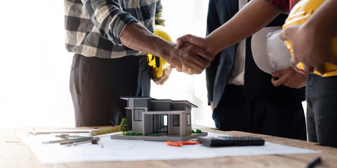 Shaking hands, Blueprints architects and building engineers talking meeting and planning will chronicle the design and technical aspects of a new house construction, renovation remodeling.
