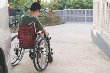 Obraz premium Behind of young man with disability thinking of something in the car park of home or hospital,school,nursery, A ramp is essential and should be designed with the safety of wheelchair users in mind.