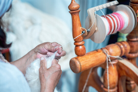 historical reconstruction of the spinning machine. hands of an adult woman work with wool