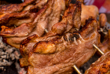 Several pieces of Liempo, or pork belly skewered on a spit and roasted on an oven at a roadside restaurant.
