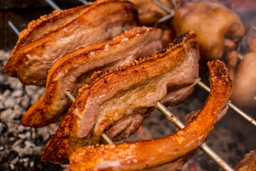 Several pieces of Liempo, or pork belly skewered on a spit and roasted on an oven at a roadside...