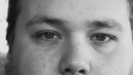 One young man smiling at camera in monochromatic black and white image. Macro eyes