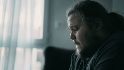 Depressed man sitting on couch. Sad unhappy person suffering from mental illness