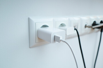 Many chargers plugged into maltiple electrical outlet on white background. Concept of electricity consumption.