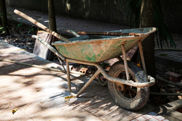 Dirty old wheelbarrow with tools in it left at a construction site. Mono wheel heavy-duty barrow with handles, contractors equipment