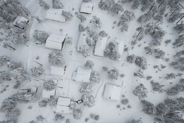 Drone aerial scenery of mountain snowy forest landscape with cottage holiday houses covered in snow. wintertime Troodos mountains Cyprus