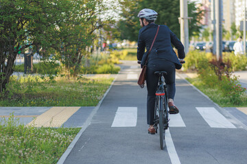 Unrecognizable middle-aged executive in black suit riding on bike lane.