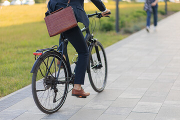 Stylish business man in suit cycling on bike on paved road outdoors.