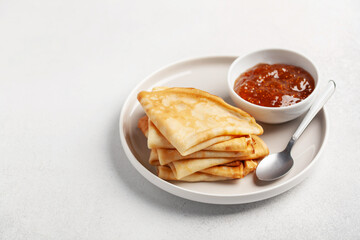 Pancakes or crepes in a plate and jam on the table. Tasty breakfast. Copy space