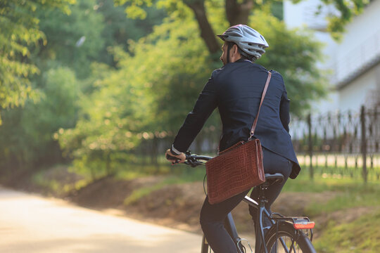 Busy male employee in suit cycling on bike to workplace.