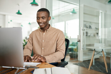 Smiling young African businessman working on a computer in an office